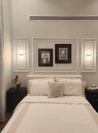 Bedroom with panelled wall detailing, framed artwork and wall lights above the bed, Project Beyond, Dubailand