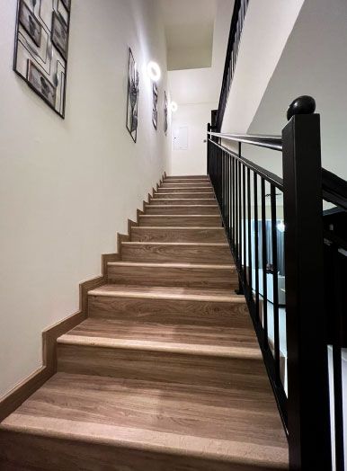 Straight staircase with wood-look treads, a black metal railing and framed pictures on the wall, Project Bold, DAMAC Hills 2
