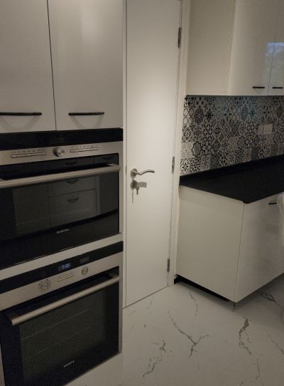 Two built-in ovens stacked in a tall unit beside the kitchen door, Project Greens, Dubai