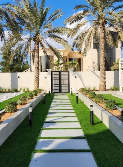 Paved entrance path through lawn and planters with path lights and palms, Project Majestic, Al Twar