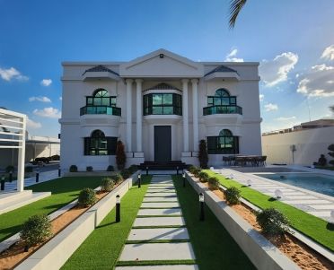 Two-storey villa facade with columns and arched windows behind a landscaped stepping-stone approach, Project Majestic, Al Twar