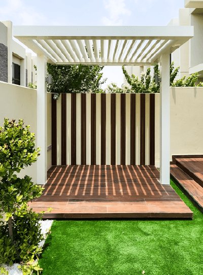 Timber-look deck platform under a white slatted pergola with a striped screen, Project Solace, Damac Hills